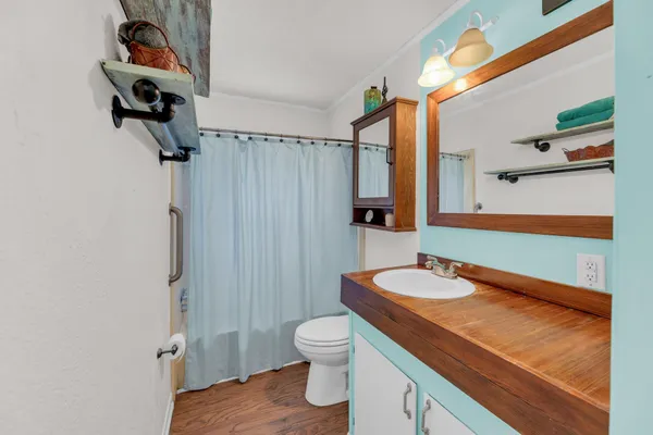 a bathroom with a granite countertop sink a toilet a mirror and shower