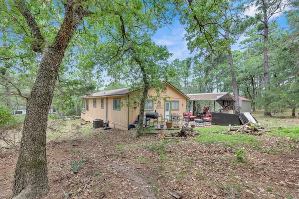 a view of a house with a yard and large trees