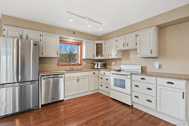 a kitchen with stainless steel appliances granite countertop a refrigerator sink and white cabinets