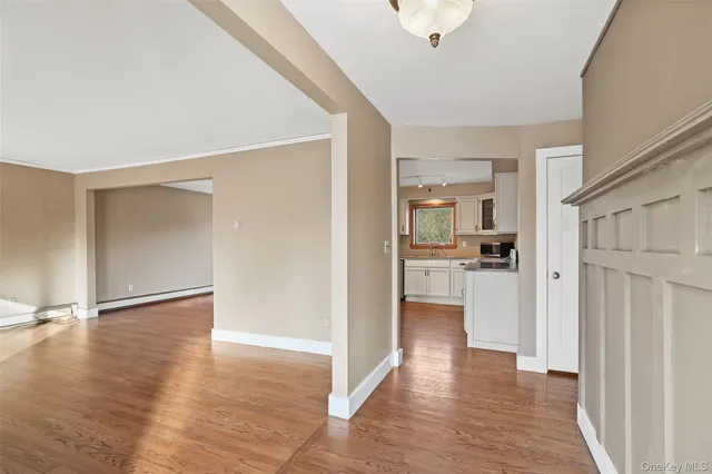 a view of a hallway with wooden floor and a kitchen