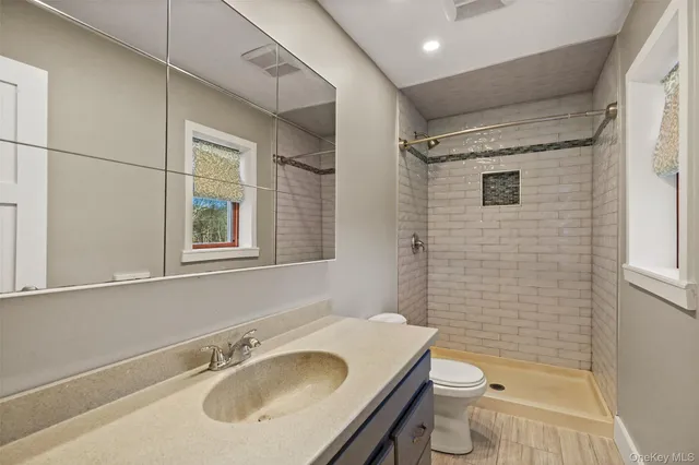 a bathroom with a sink toilet vanity and shower