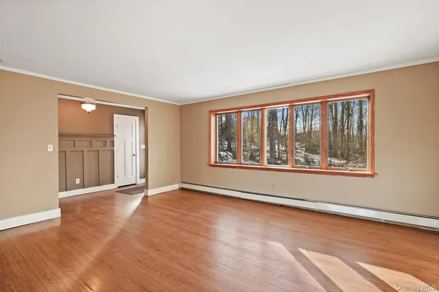 a view of an empty room with a window and wooden floor
