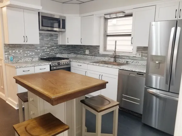 a kitchen with stainless steel appliances granite countertop a sink stove microwave and refrigerator