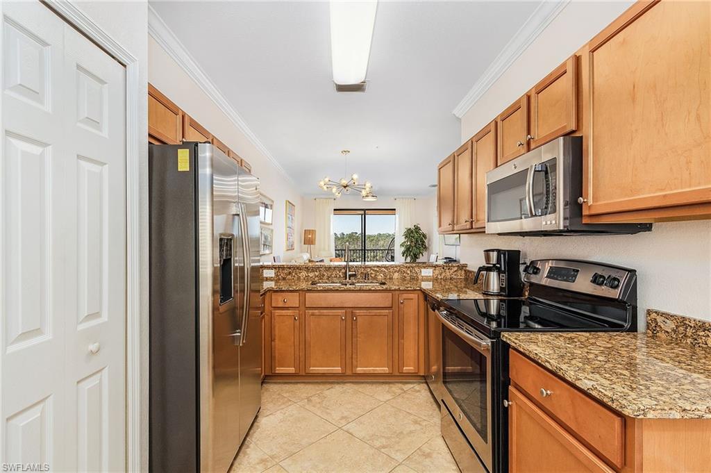 9731 Acqua Court, Unit 543 Naples, FL 34113 - Photo 4 of 24 a kitchen with stainless steel appliances granite countertop a stove and a refrigerator