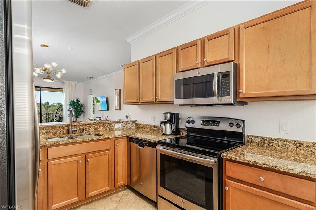9731 Acqua Court, Unit 543 Naples, FL 34113 - Photo 6 of 24 a kitchen with stainless steel appliances granite countertop a sink stove and microwave