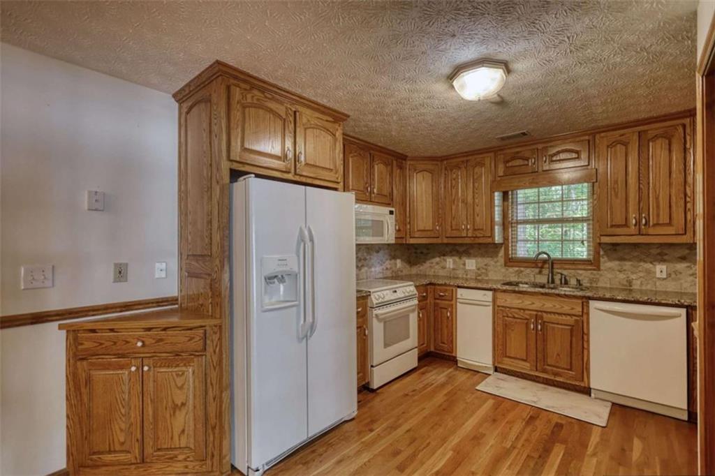 255 Old Hardy Farm Road Jackson, GA 30233 - Photo 56 of 78 a kitchen with stainless steel appliances granite countertop a refrigerator a stove a sink and dishwasher with wooden floor