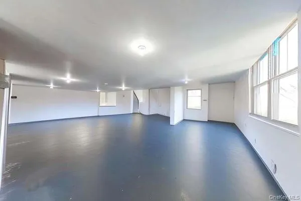 an empty room with hard wood floors and windows