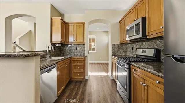 a kitchen with granite countertop a refrigerator stove and sink
