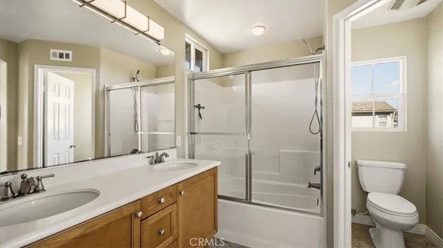 a bathroom with a double vanity sink toilet mirror and shower