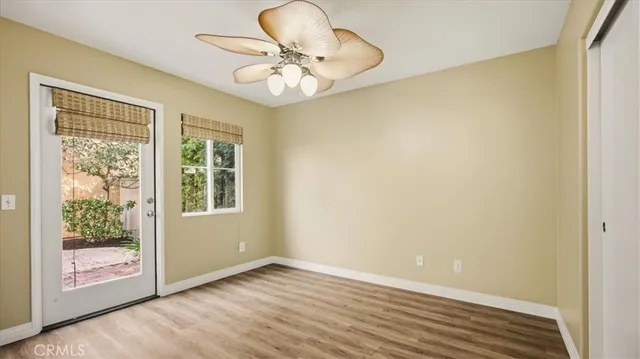 an empty room with wooden floor fan and windows