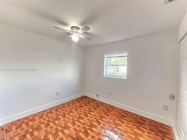 an empty room with a window and ceiling fan
