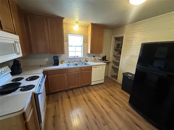 a kitchen with a sink a stove cabinets and a wooden floor