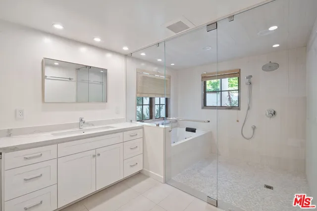 a spacious bathroom with double vanity a mirror and shower