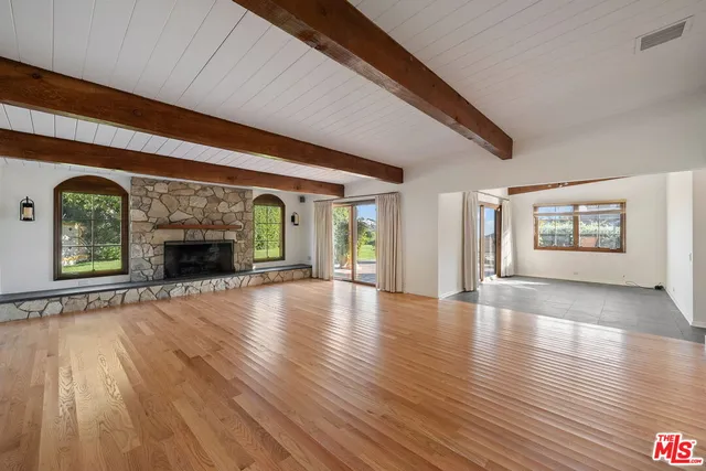 a view of an empty room with wooden floor fireplace and a window