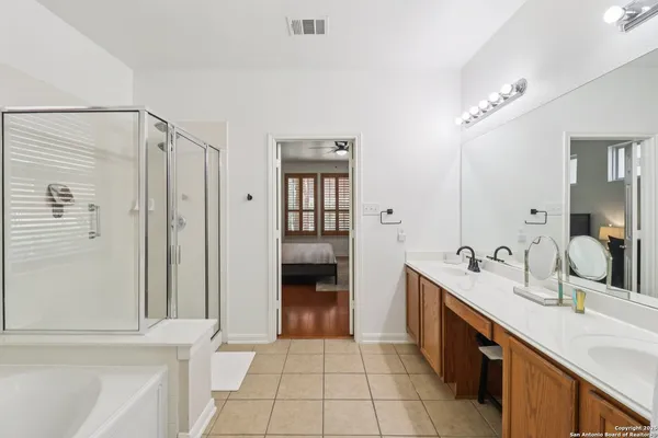 a bathroom with a double vanity sink a large mirror and a bathtub