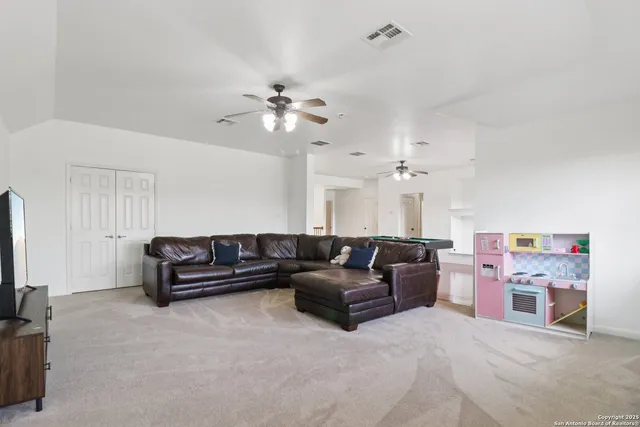 a living room with furniture a ceiling fan and a flat screen tv