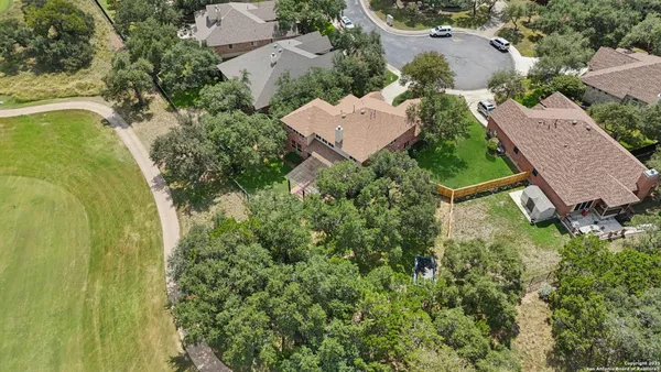 an aerial view of residential house with outdoor space and trees all around