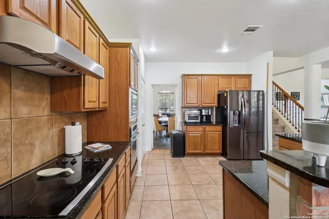 a kitchen with stainless steel appliances granite countertop a refrigerator a stove and a sink