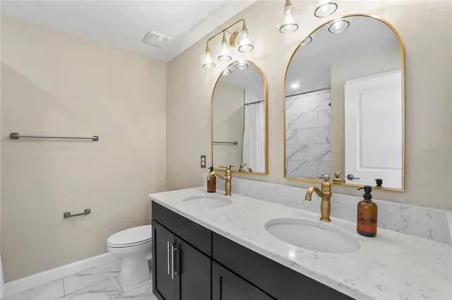 a bathroom with a granite countertop sink a toilet and a mirror