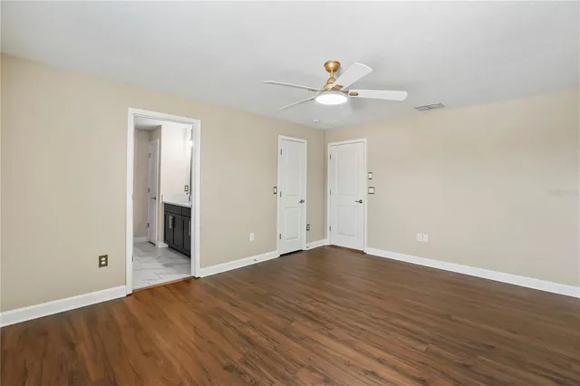 an empty room with wooden floor fan and windows