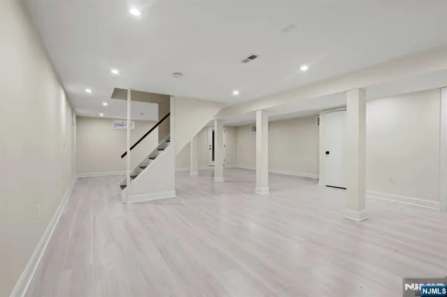a view of an empty room with wooden floor and stairs