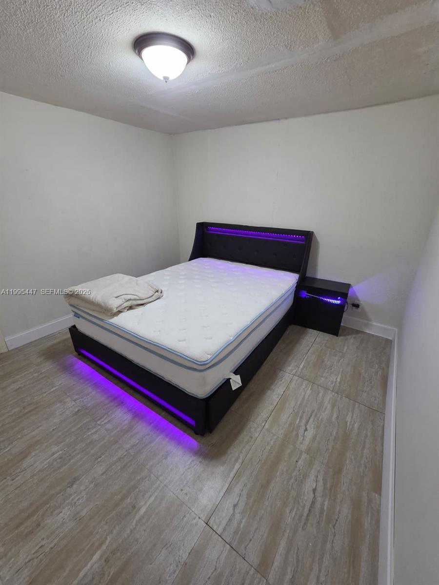 1420 Southwest 129th Court, Unit 1 Miami, FL 33184 - Photo 8 of 11 a bed sitting in a bedroom next to a window