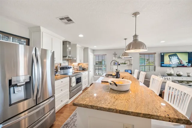 a kitchen with stainless steel appliances granite countertop a refrigerator a stove and a sink