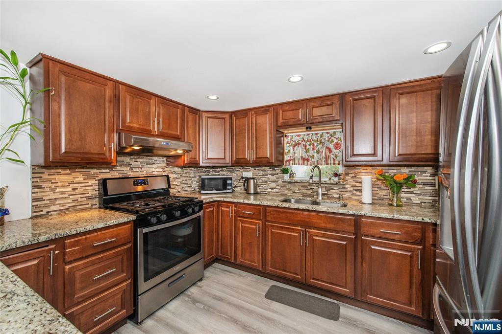 39 Helen Drive Moonachie, NJ 07074 - Photo 12 of 20 a kitchen with stainless steel appliances granite countertop wooden cabinets a stove top oven a sink and dishwasher with wooden floor