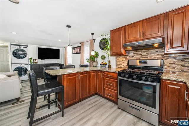 a kitchen with stainless steel appliances a stove a sink cabinets and a wooden floor