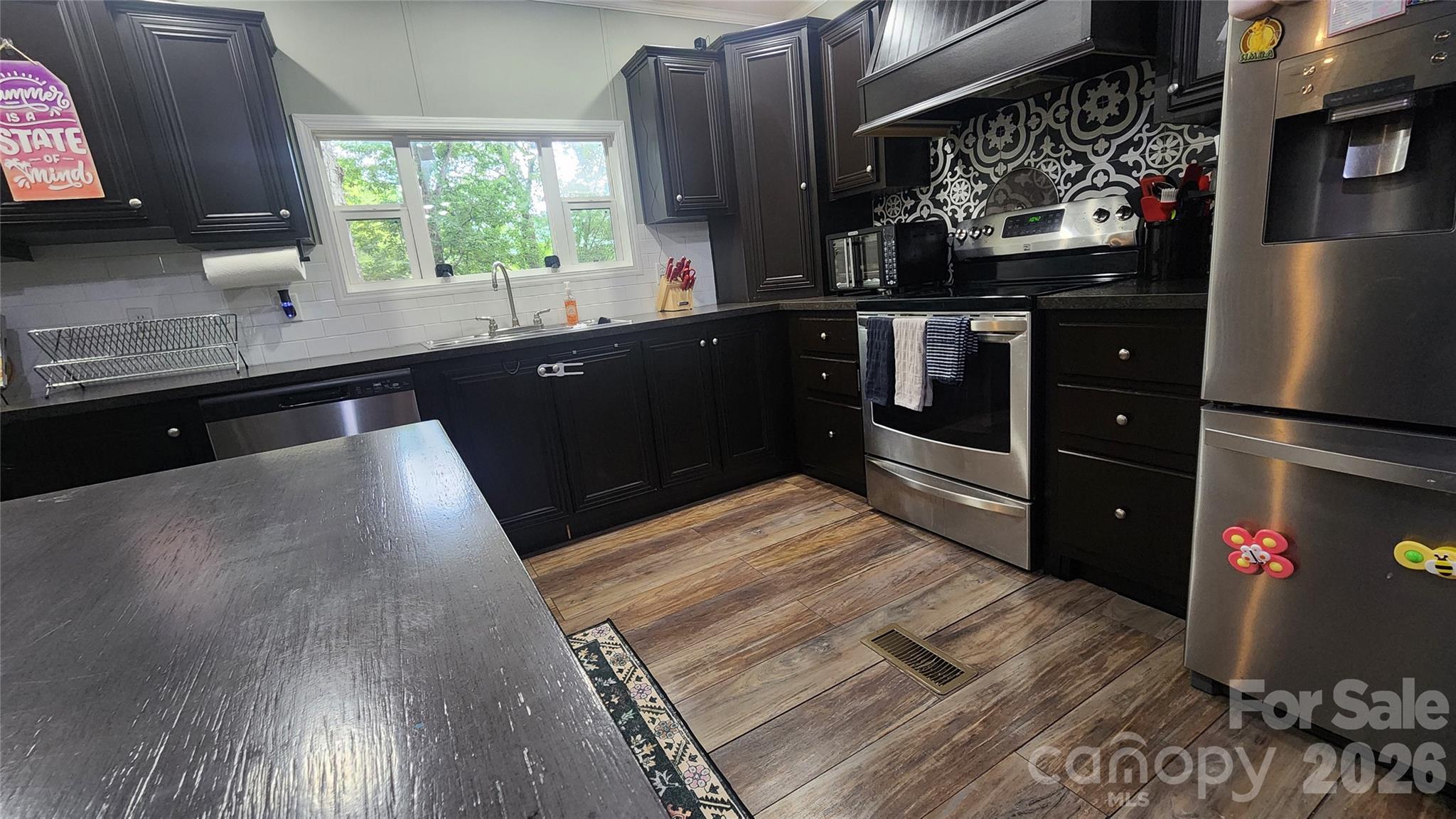 67 Indian Trail Road Candler, NC 28715 - Photo 19 of 31 a kitchen with stainless steel appliances granite countertop a refrigerator a sink and wooden cabinets