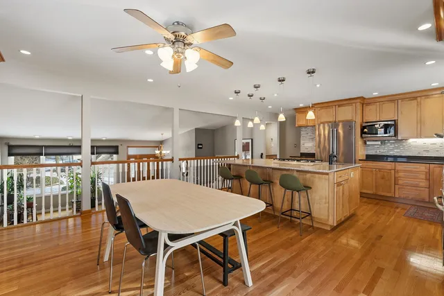 a kitchen with stainless steel appliances kitchen island granite countertop a table chairs and a wooden floor