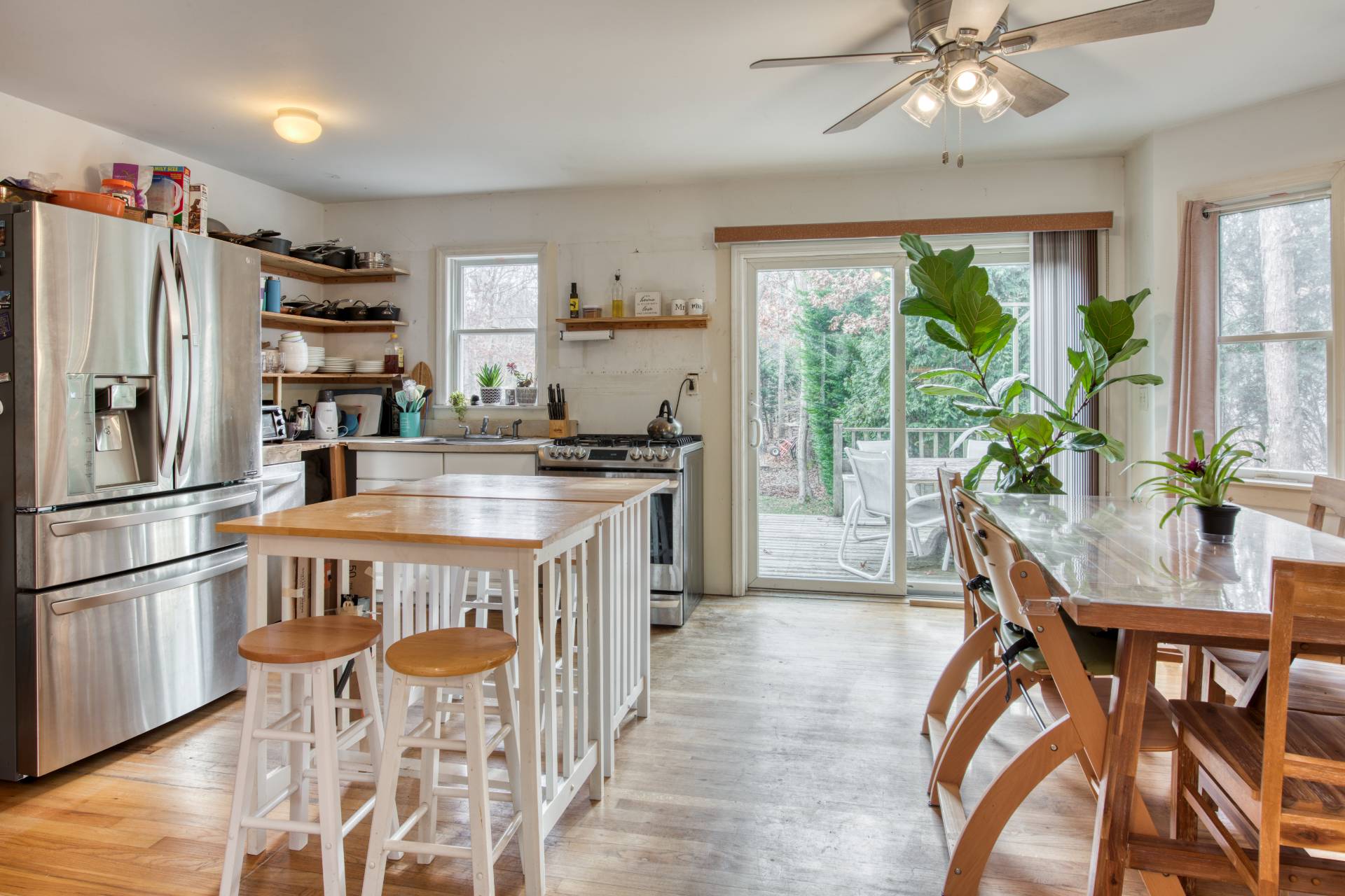 a kitchen with stainless steel appliances granite countertop a stove a refrigerator a microwave a dining table and chairs with wooden floor