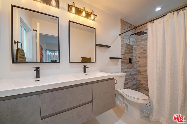 a bathroom with a sink a toilet a mirror and shower