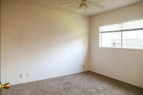 an empty room with a chandelier fan and windows
