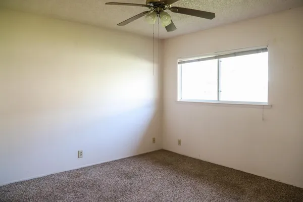 an empty room with a window and a fan