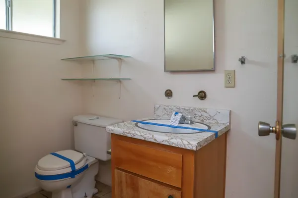 a bathroom with a granite countertop toilet sink and mirror