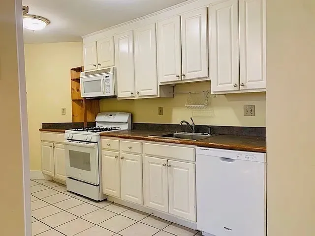 a kitchen with granite countertop white cabinets and white appliances