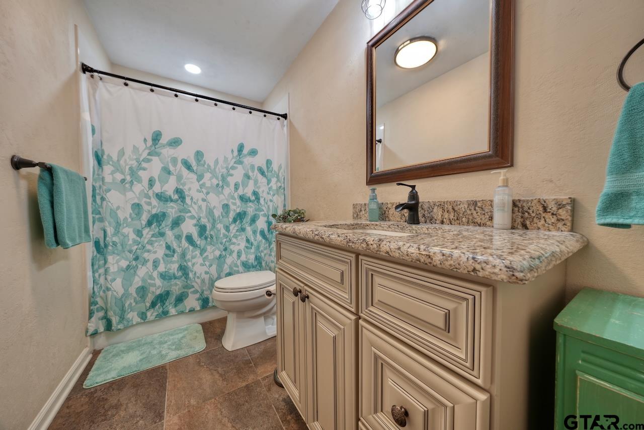11656 Constantine Avenue Tyler, TX 75708 - Photo 19 of 26 a bathroom with a granite countertop sink a toilet and a mirror
