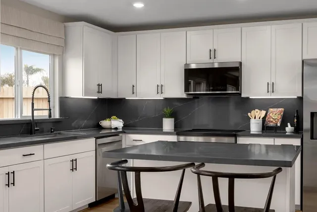 a kitchen with granite countertop a stove a sink and white cabinets