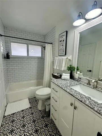 a bathroom with a granite countertop toilet a sink a mirror a bathtub and shower