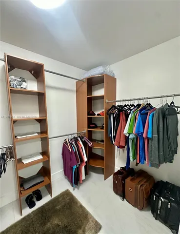 a view of walk in closet with clothes and shoes