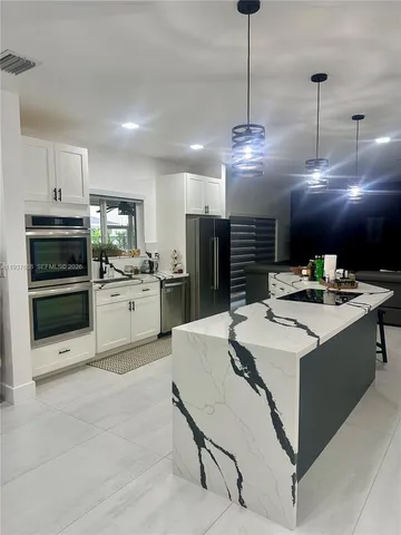 a large kitchen with kitchen island a sink a stove and chairs