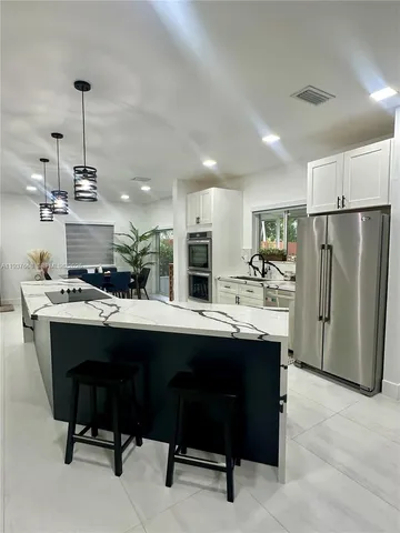 a kitchen with a sink a refrigerator a stove and chairs with wooden floor