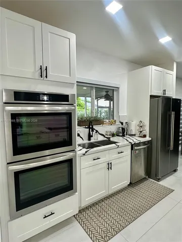 a kitchen with stainless steel appliances white cabinets and a stove a oven with white countertops