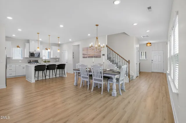 a kitchen with stainless steel appliances granite countertop a sink a stove a refrigerator and white cabinets with wooden floor