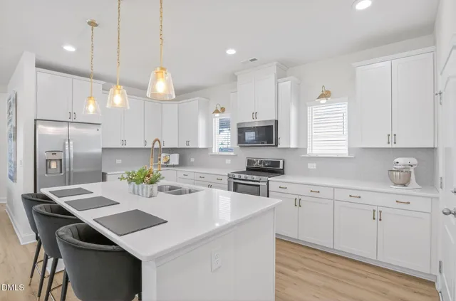 a kitchen with a sink a stove a refrigerator and white cabinets