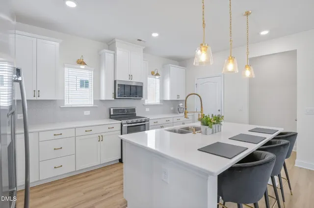 a kitchen with stainless steel appliances granite countertop a sink a stove and a wooden floor