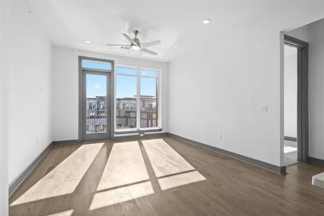 an empty room with wooden floor fan and windows