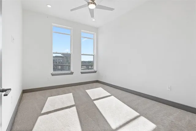 an empty room with windows and ceiling fan