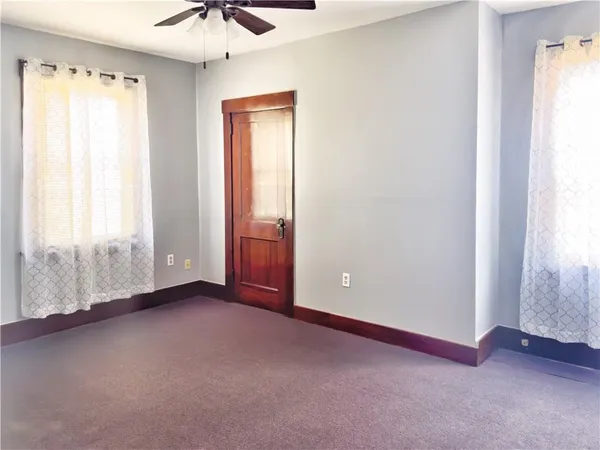 an empty room with windows and a chandelier fan